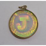 A gold coloured metal hologram pendant with the initial 'J' 11