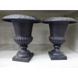 A pair of patinated iron campana design vases,