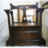 A 1920s stained oak combination hall seat/stickstand with a low, open back and arms,