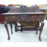 A late 19thC profusely carved hall table, decorated with mask motifs,