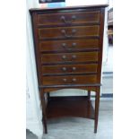 An Edwardian string and ebony inlaid mahogany six drawer music cabinet, raised on square,