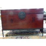 A modern Chinese lacquered fruitwood chest with a hinged lid and a pierced cast metal lock,
