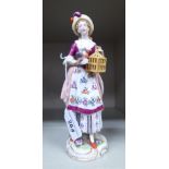 A late 19th/early 20thC Naples porcelain figure, a young woman wearing a floral pinafore dress,