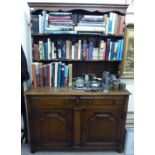 A modern oak dresser surmounted by a two tier plate rack, over two drawers and two cupboard doors,