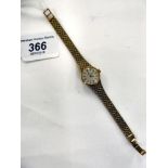 A lady's 9ct gold Omega, round cased wristwatch, faced by a baton dial, on a flexible,