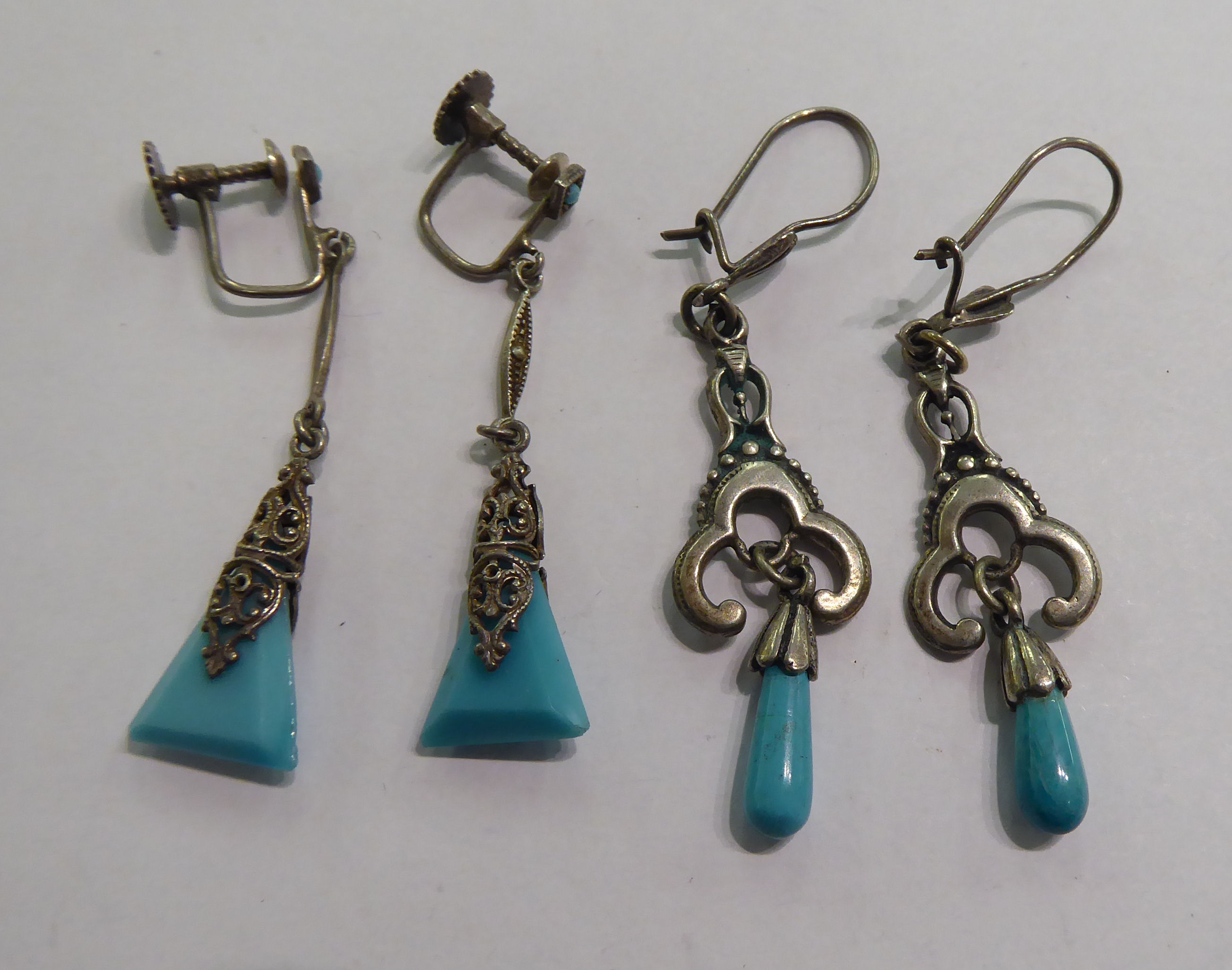 Two similar pairs of white metal earrings,