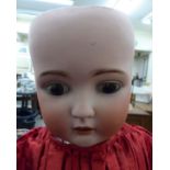 An early 20thC German bisque head doll with painted features and weighted sleeping eyes,