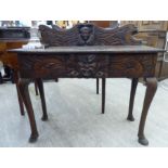 A late 19thC profusely carved hall table, decorated with mask motifs,