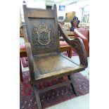A 1920s oak framed Glastonbury design armchair, the panelled and carved back,