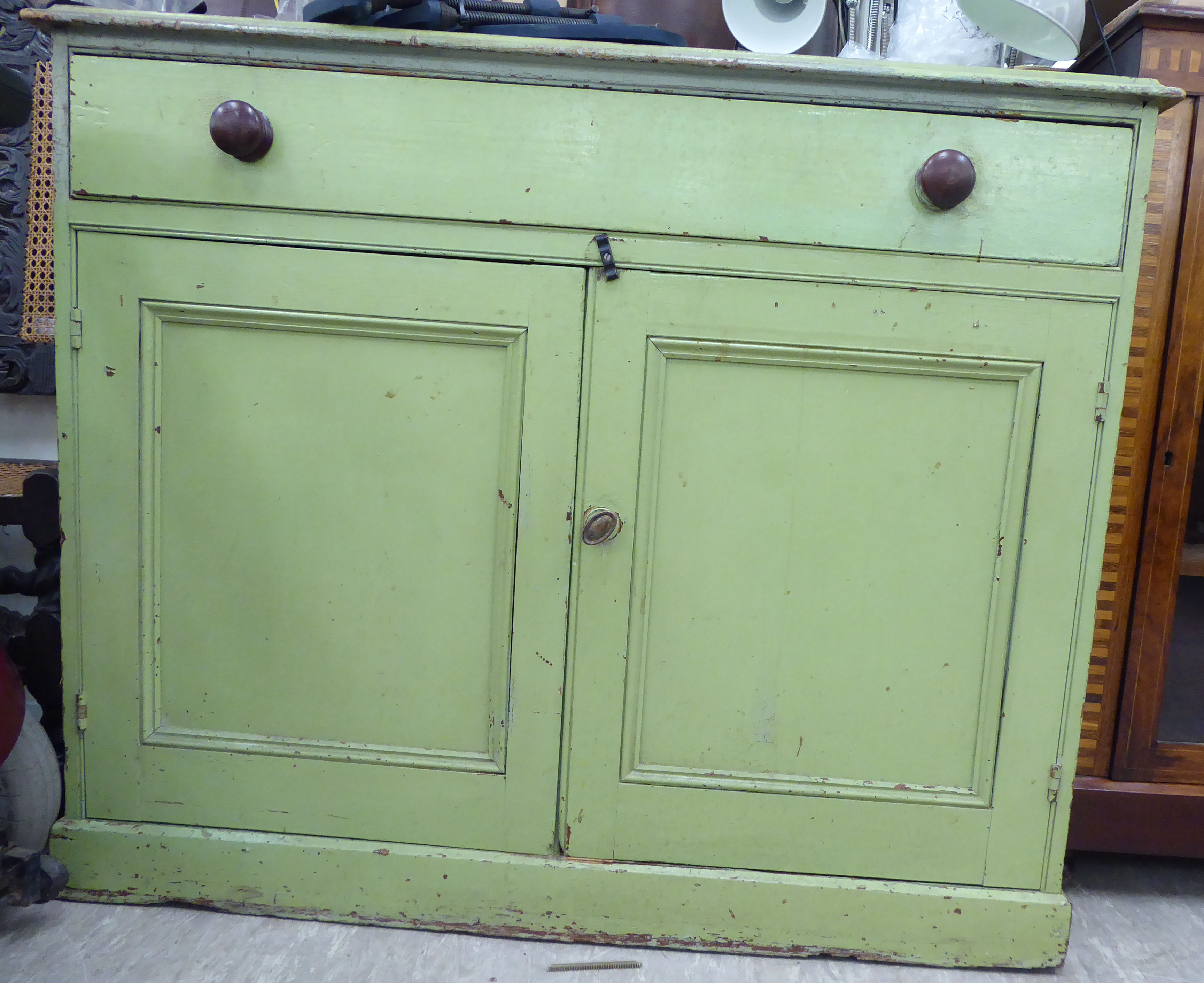 A late Victorian green painted pine side cabinet with a drawer and two doors,