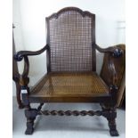 An early 20thC stained beech framed open arm bergere chair,
