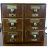 An early 20thC honey coloured oak desk top, six drawer file index cabinet with brass handles,
