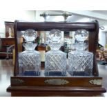 A mahogany tantalus with silver plated mounts,