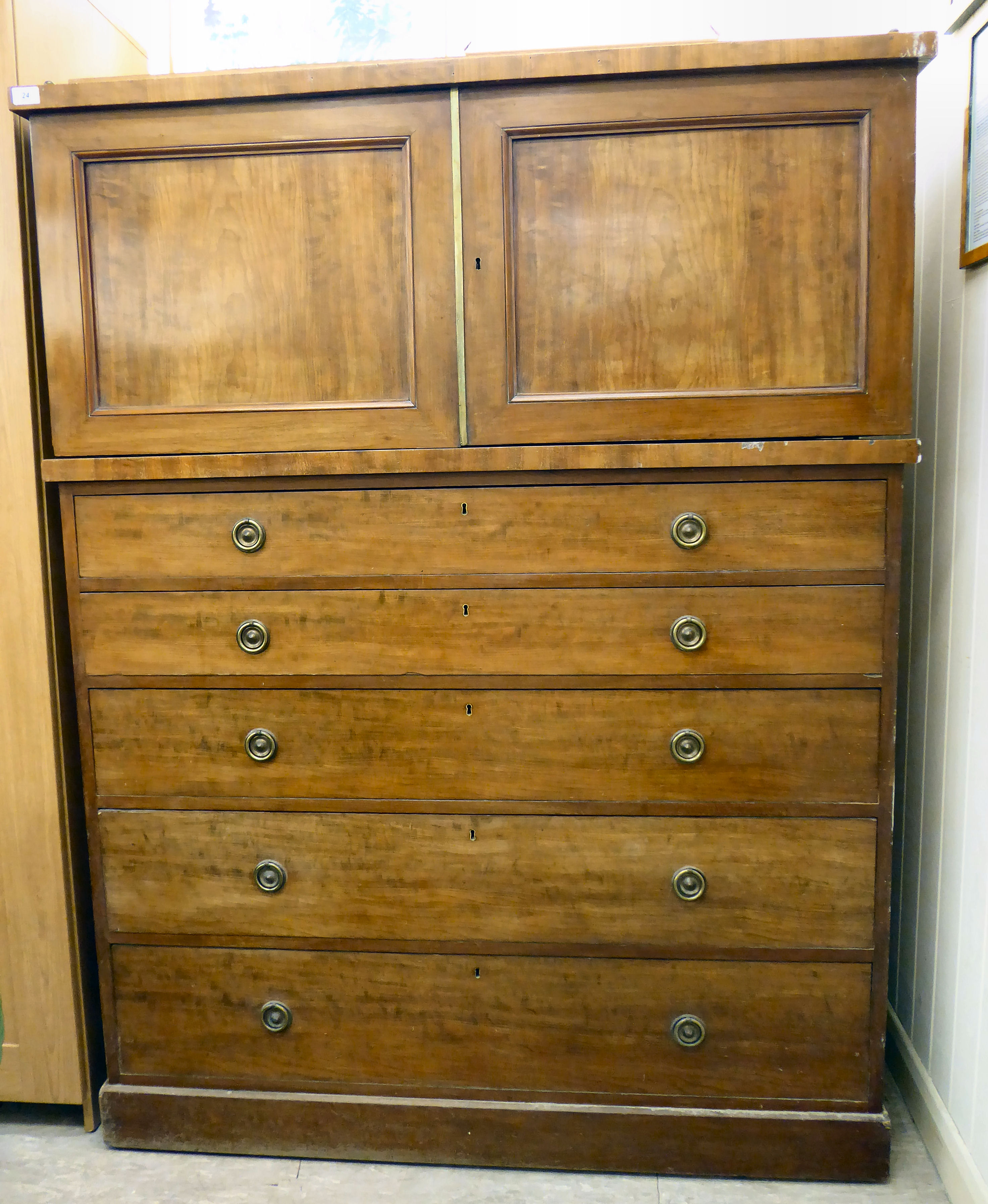 A mid 19thC mahogany linen chest with a pair of panelled doors, over five graduated drawers,