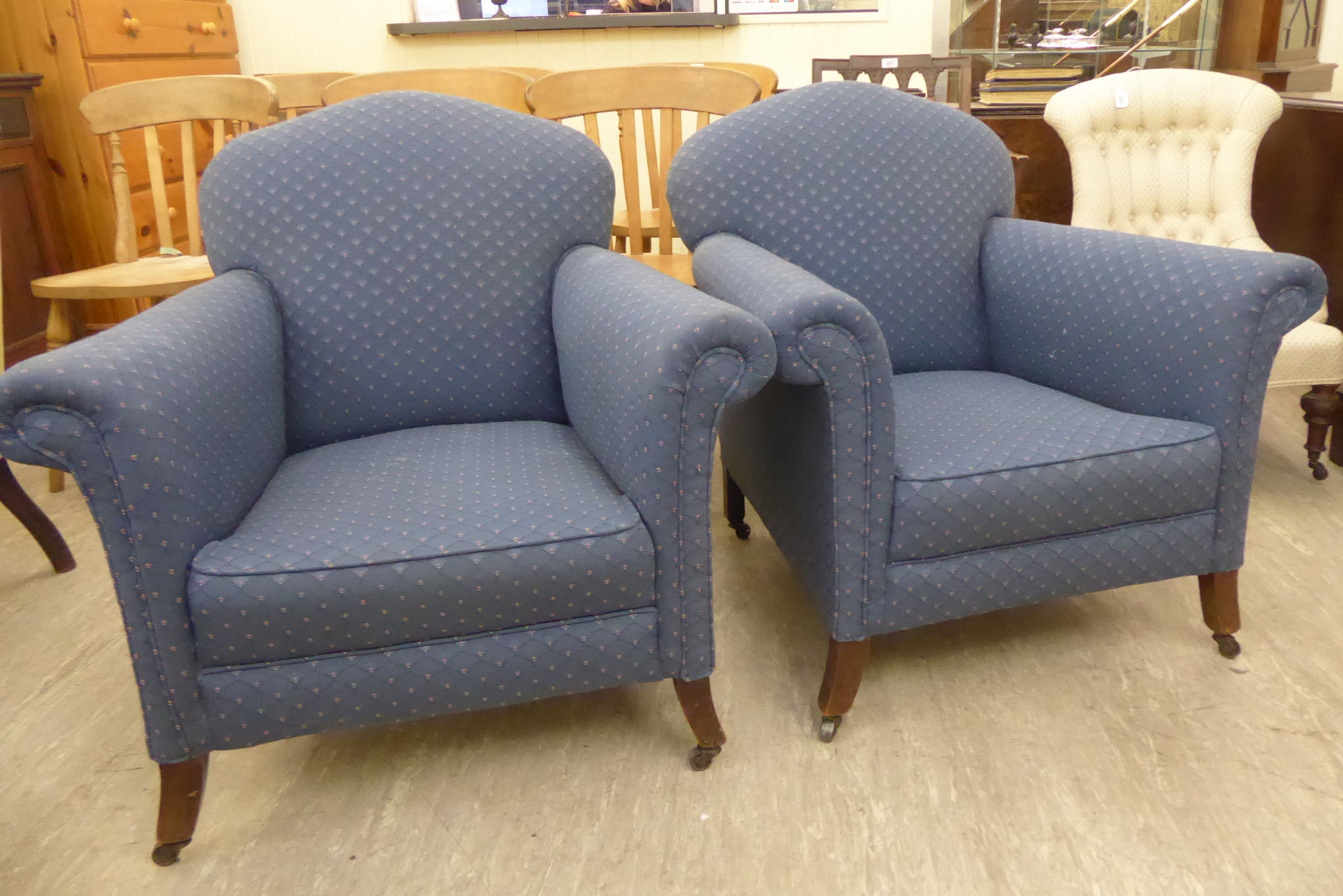 A pair of 1920s fireside chairs with arched, low backs and scrolled, level arms,