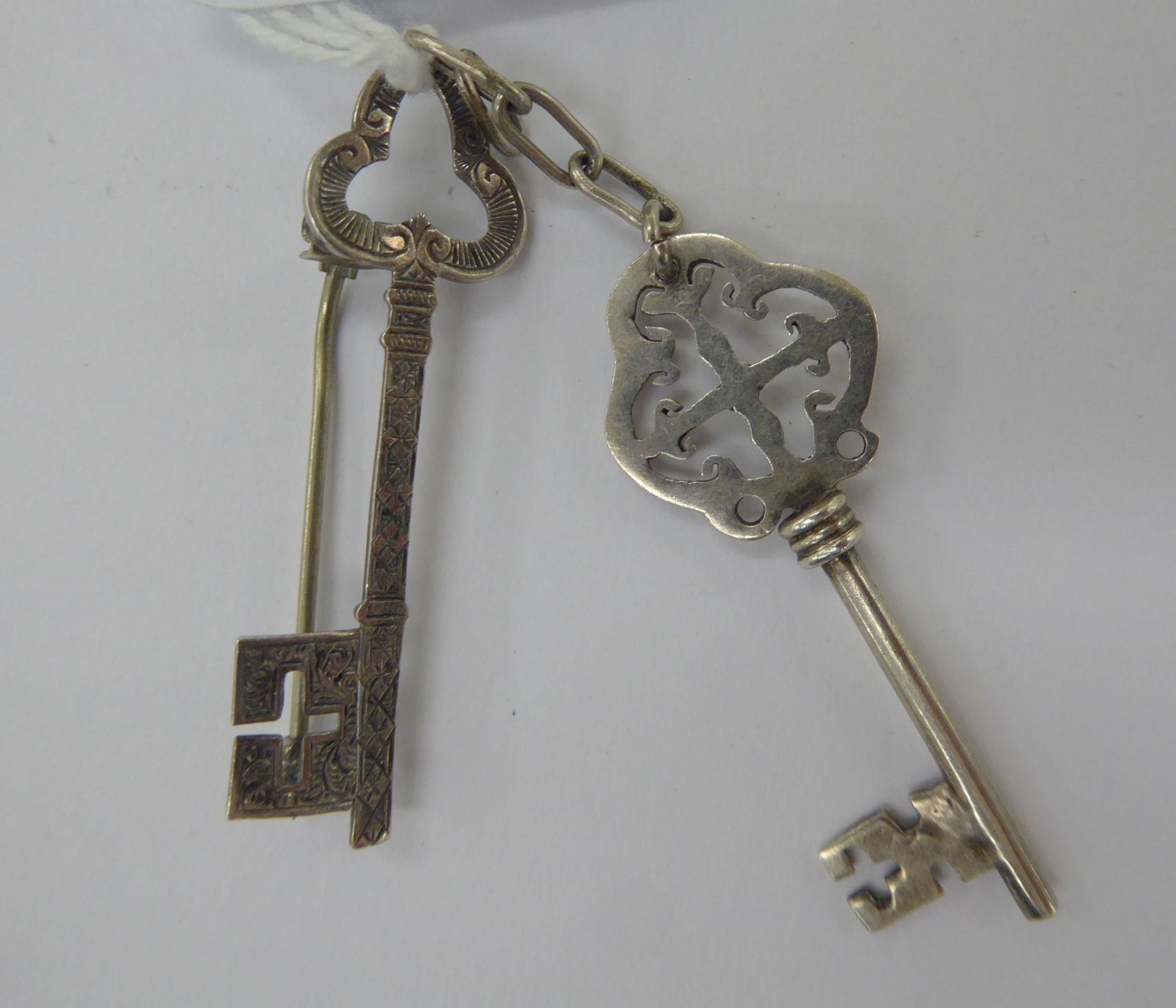 An 'antique' silver coloured metal key design pendant;