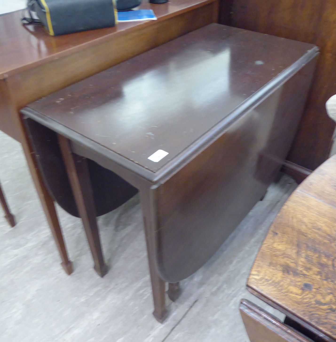 A modern mahogany Pembroke style dining table with an oval top, raised on moulded,