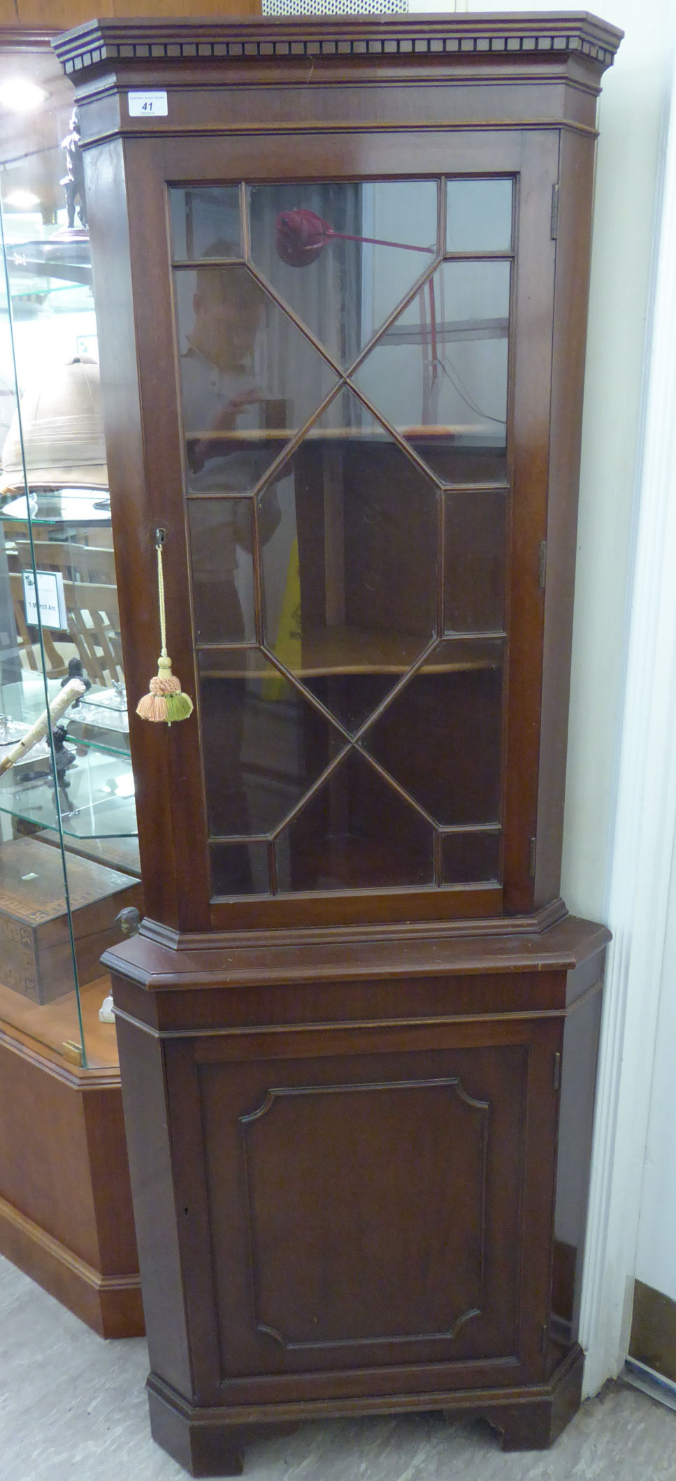 A modern mahogany finished standing corner cupboard with a glazed door, over a cupboard door,
