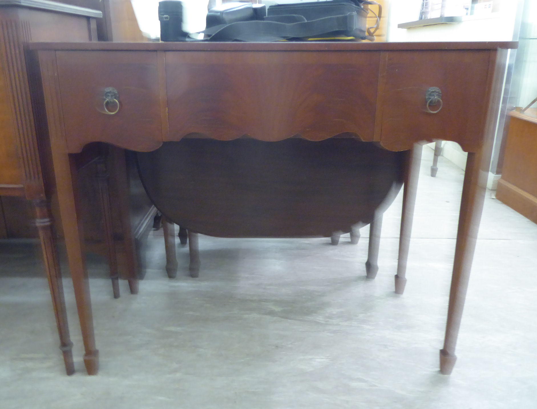 A modern mahogany finished serpentine front serving table, comprising three in-line drawers,