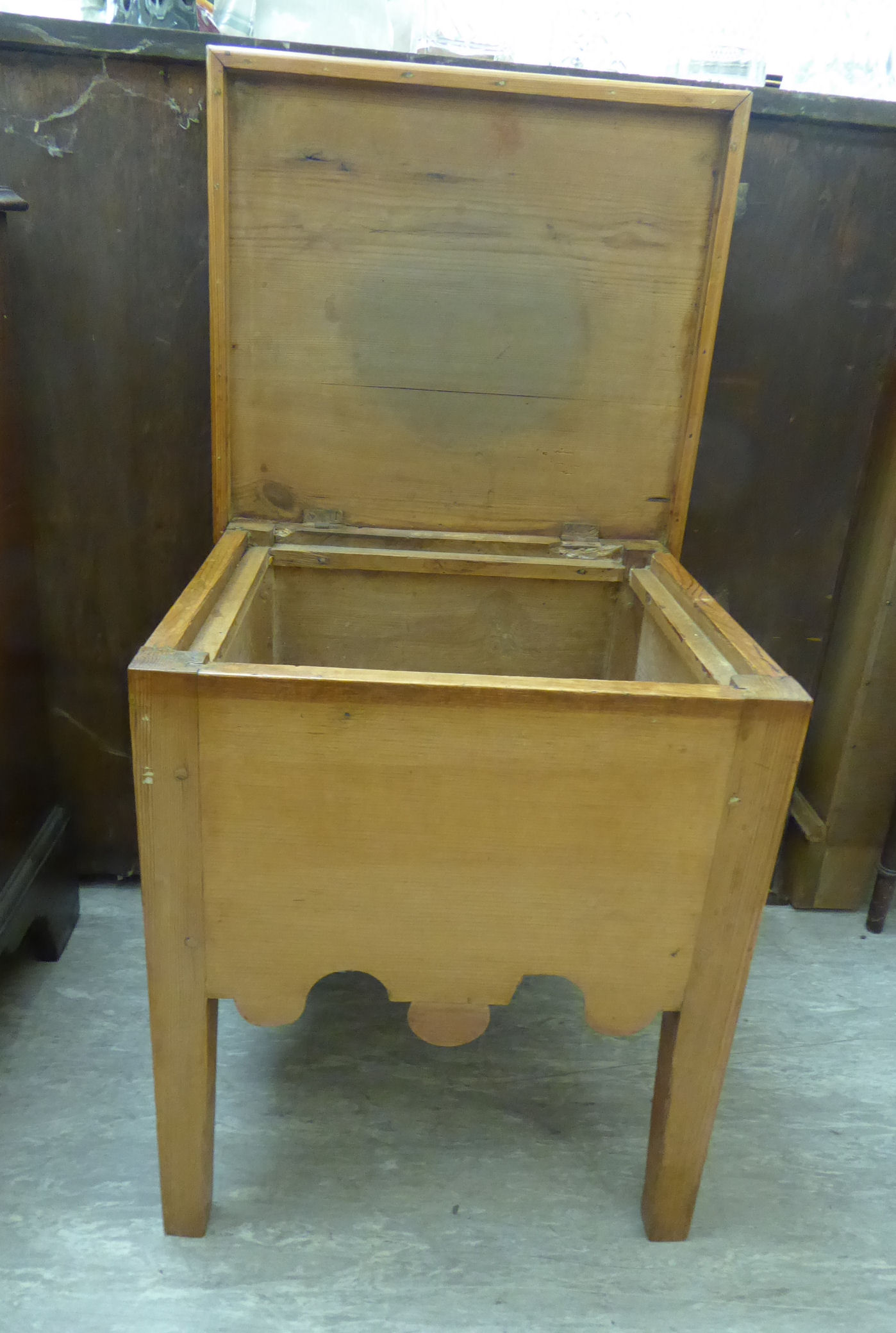 A late Victorian pitch pine 'night commode' cabinet with a rising top box seat and modesty apron,