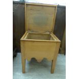 A late Victorian pitch pine 'night commode' cabinet with a rising top box seat and modesty apron,