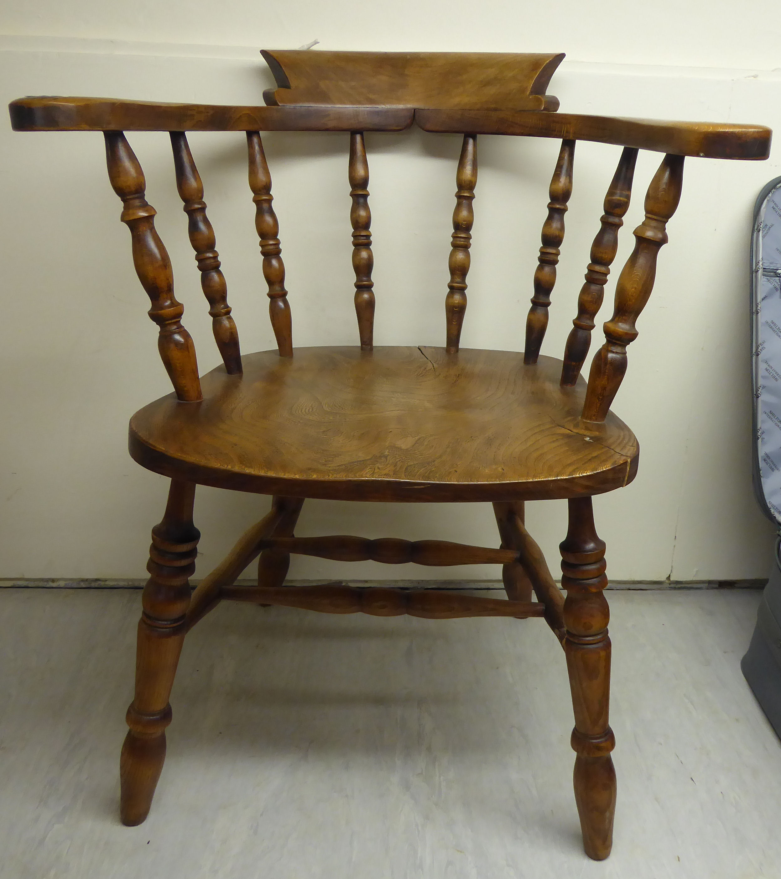 A mid 20thC beech and elm framed captains chair with a horseshoe shaped, spindled back,