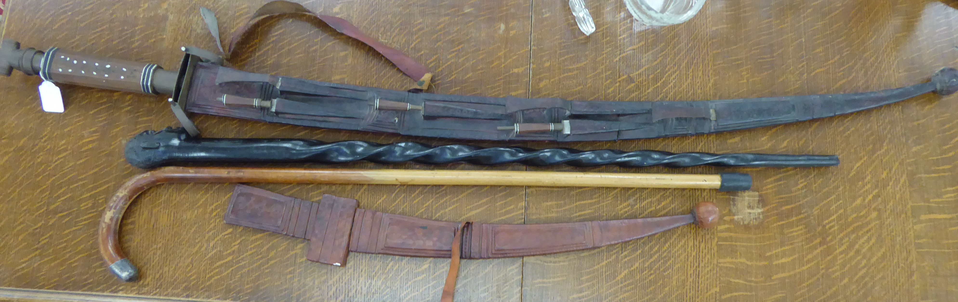 20thC edged weapons and walking aids: to include an Indian sword with a hide sheath the curved