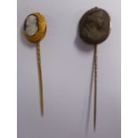 Two yellow metal stickpins, one set with an oval, moulded earthenware plaque,