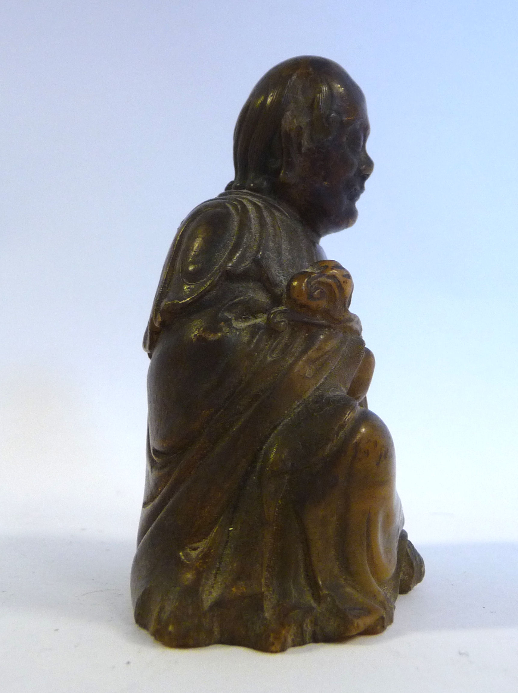 A 19thC Chinese carved brown soapstone seated, robed figure holding a lotus flower, - Image 2 of 6