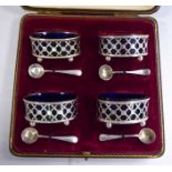 A set of four silver oval framed salt cellars with blue glass liners,