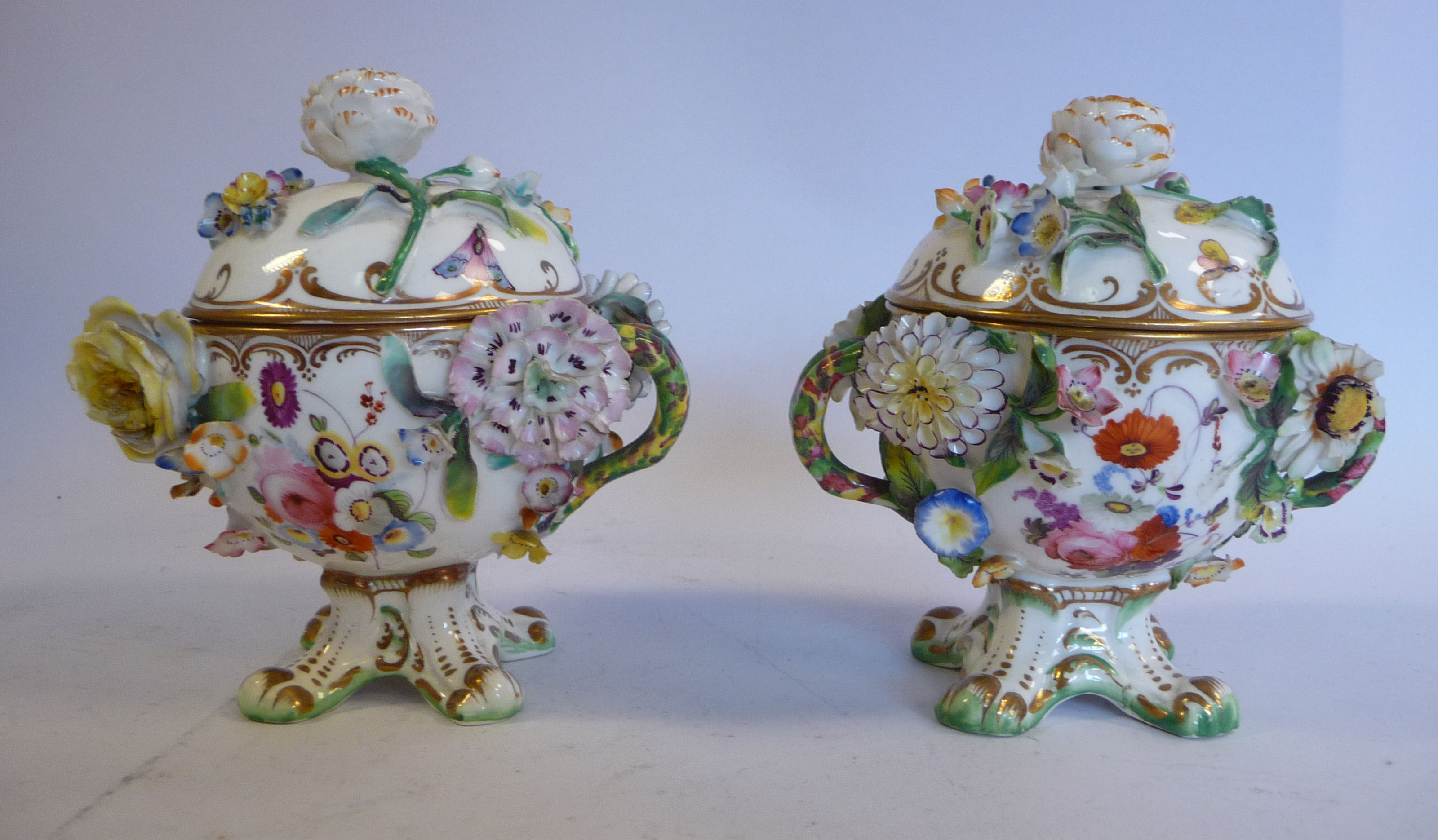 A pair of late 19thC floral encrusted porcelain, twin handled pots with domed covers,