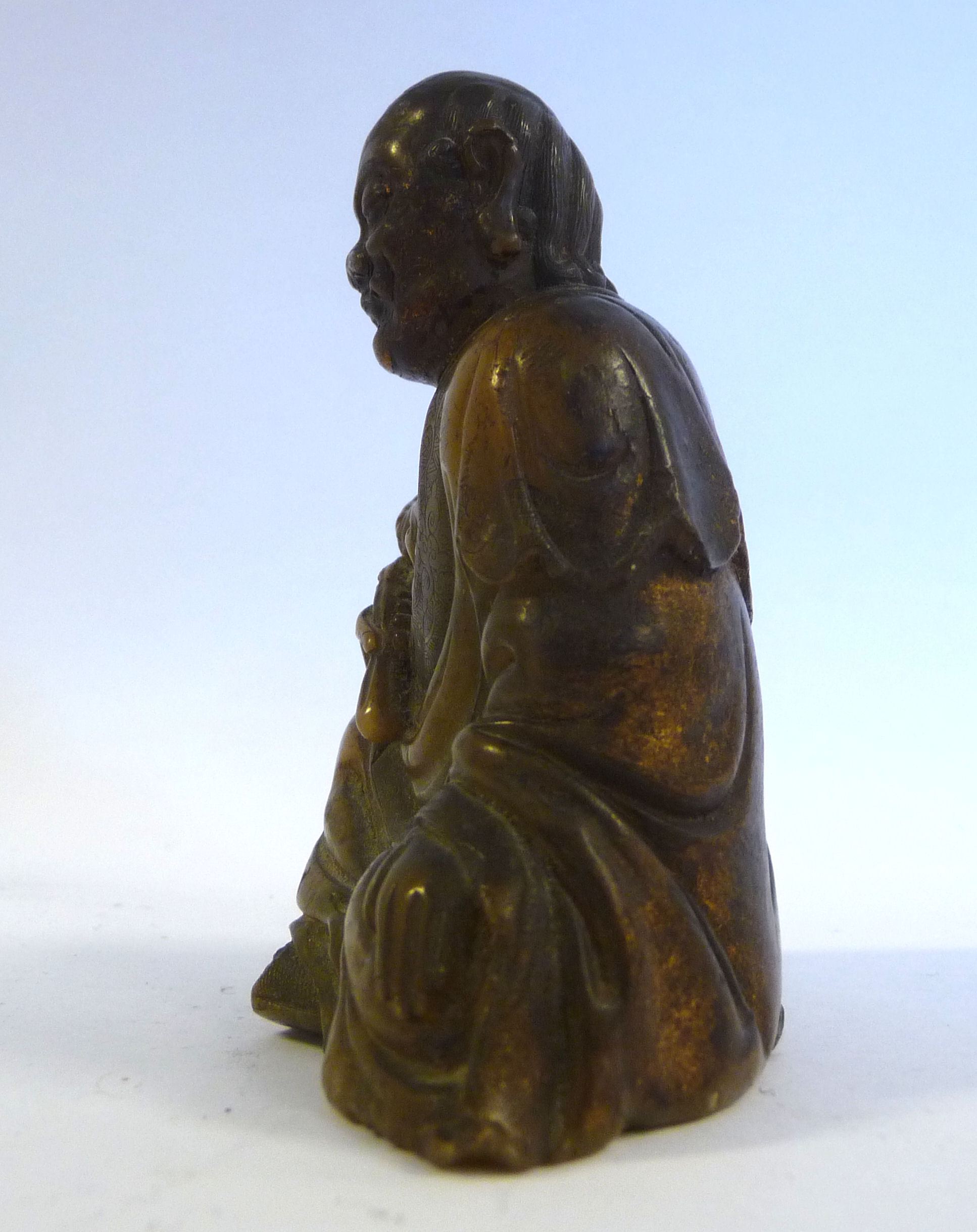 A 19thC Chinese carved brown soapstone seated, robed figure holding a lotus flower, - Image 4 of 6