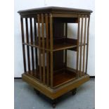 An Edwardian ebony string inlaid and crossbanded mahogany revolving two tier bookcase with slatted