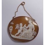 An oval shell carved cameo pendant, featuring a seated classical maiden with a cherub at her side,