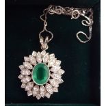 A platinum pendant, set with an oval emerald and diamonds,