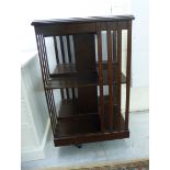 An Edwardian mahogany two tier revolving bookcase with slatted sides,