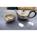 A silver teapot of squat,