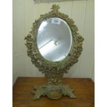 A late 19thC oval, bevelled toilet mirror, set in a decoratively cast brass frame,