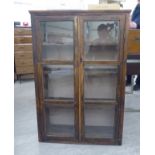 A mid 20thC mahogany finished and pine bookcase with a pair of glazed doors, enclosing four shelves,