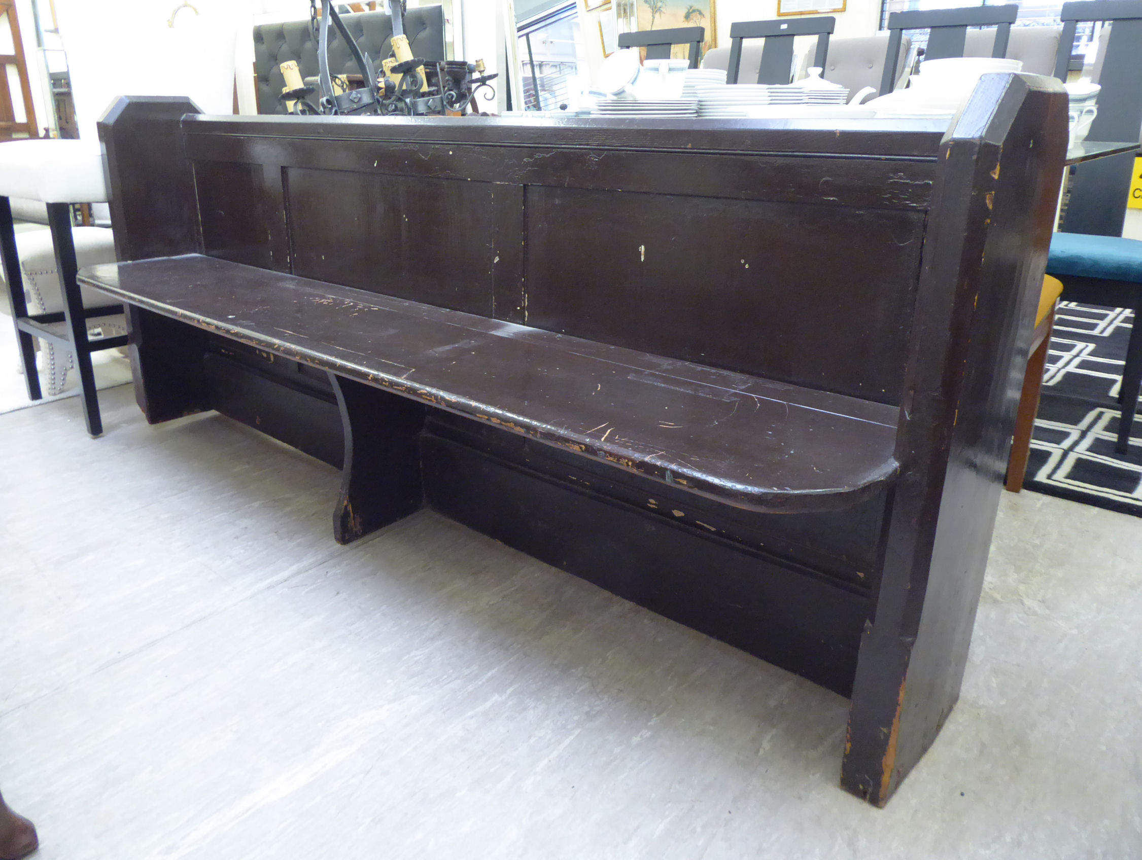 An early 20thC later chocolate brown painted pine pew with a low, level, panelled back,