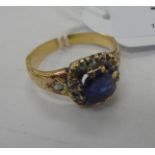 A yellow metal ring, claw set with a sapphire,