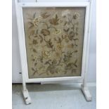 A 1920s white painted beech framed firescreen,