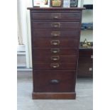 An early 20thC stained pine eight drawer pedestal filing cabinet chest,