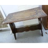 An Arts & Crafts inspired planked oak occasional table with relief carved ribbon and quarterfoil