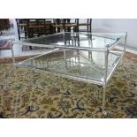 A modern polished steel framed coffee table with a bevelled clear glass top and undertier,