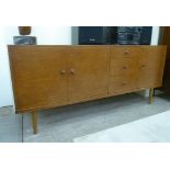 A 1970s teak sideboard, comprising an arrangement of doors and drawers, raised on turned,