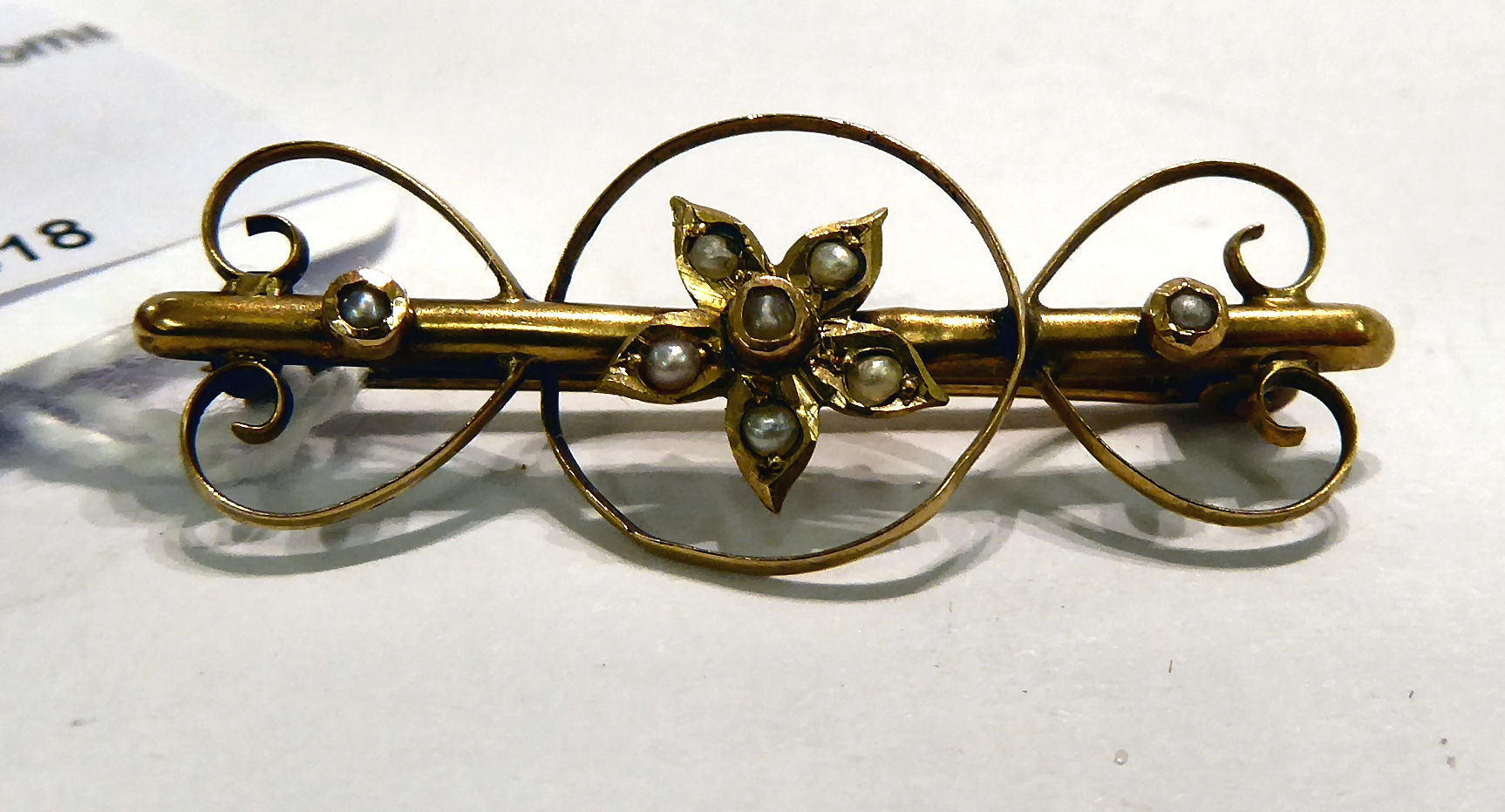 An 'antique' gold coloured metal brooch with floral, heart shaped and C-scrolled ornament,