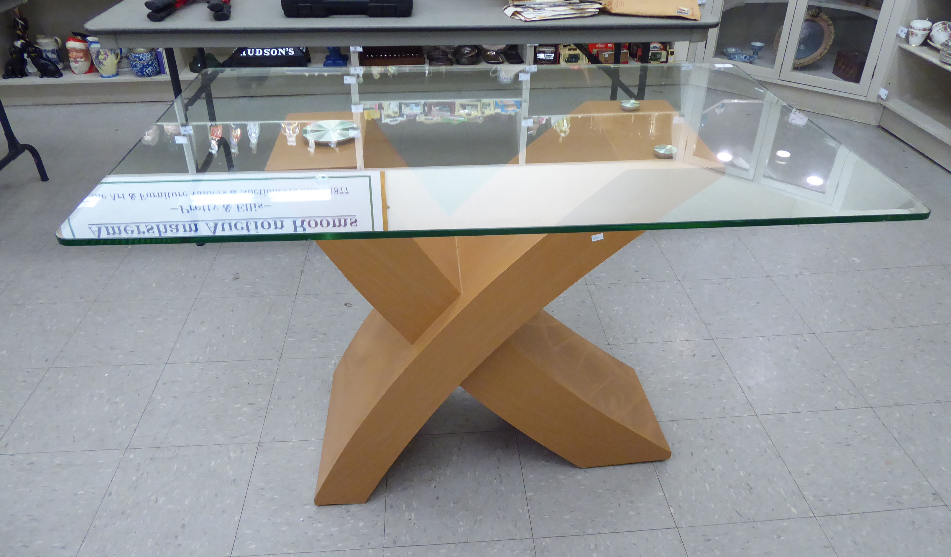 A modern centre table, the clear plate glass top elevated on a light coloured, beech finished,