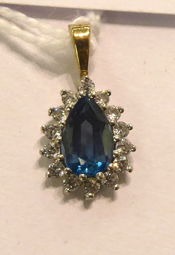 A white metal pendant, claw set with a blue topaz,