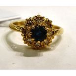 An 18ct gold cluster ring, set with a raised sapphire,